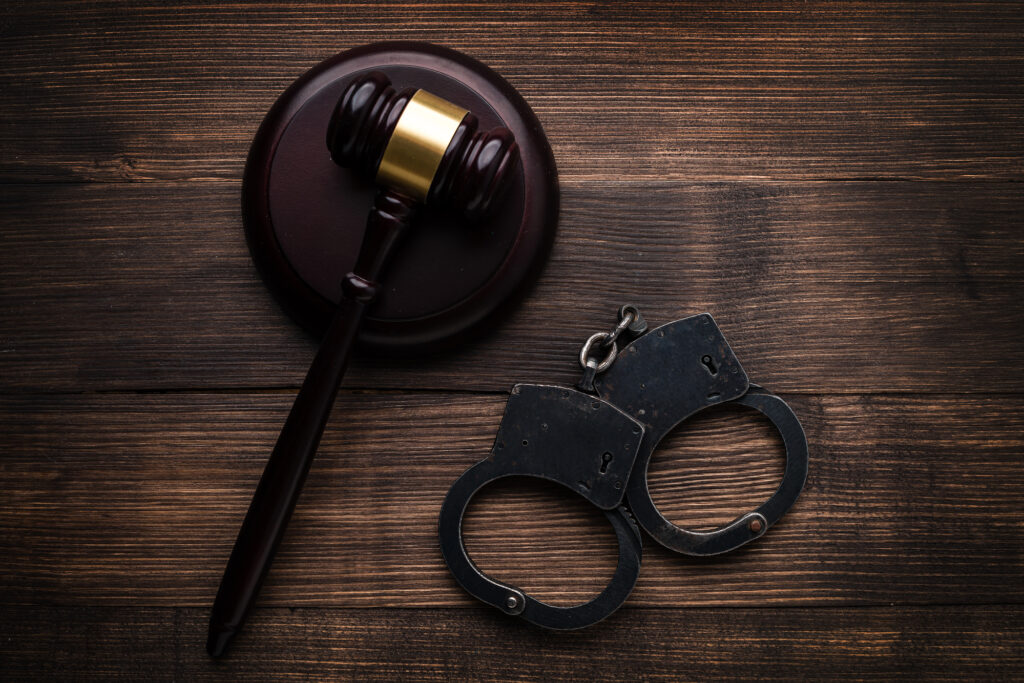 federal gang charges or federal RICO charges - Gavel with stand and handcuffs on a wooden background top view